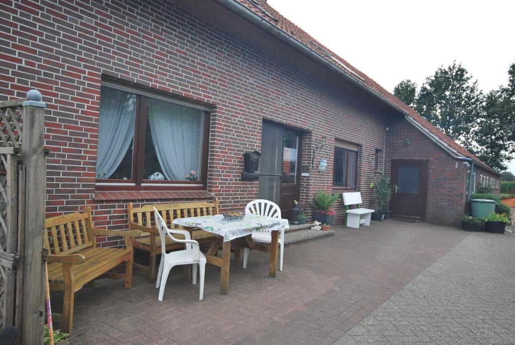 un patio con mesa y sillas y un edificio en Ferienhof Wiesenblick 35519, en Uplengen