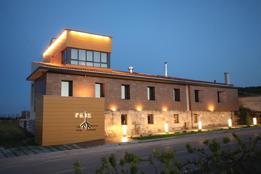 a brick building with a sign in front of it at Hotel Raíz in Roa