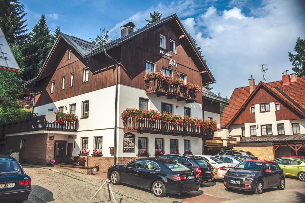 un grand bâtiment avec des voitures garées devant lui dans l'établissement Pension Luky, à Špindlerův Mlýn