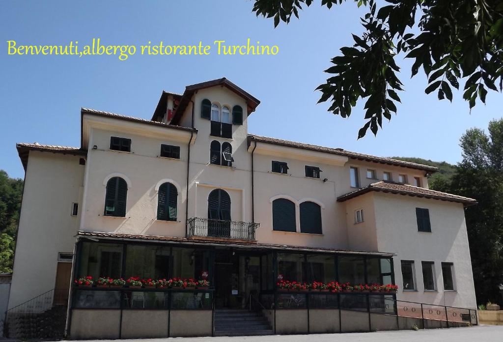 a large white building with flowers in front of it at Albergo Ristorante Turchino in Campo Ligure