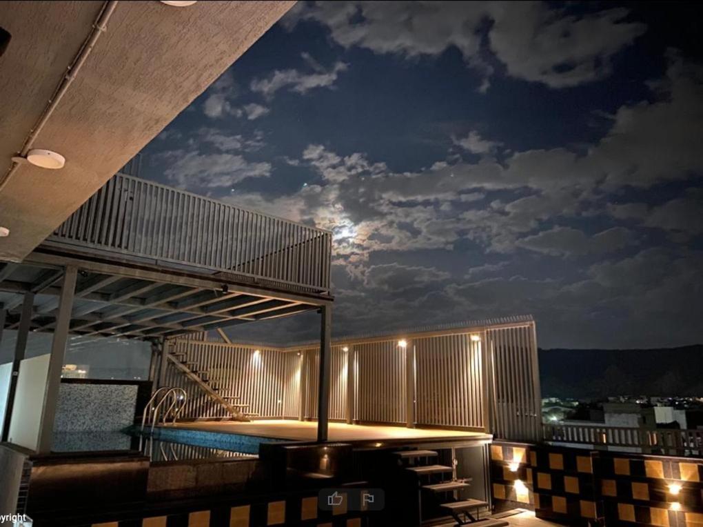 a balcony with a table and a pool at night at Ka10 SQUARE HOTEL & BANQUETS in Jaipur