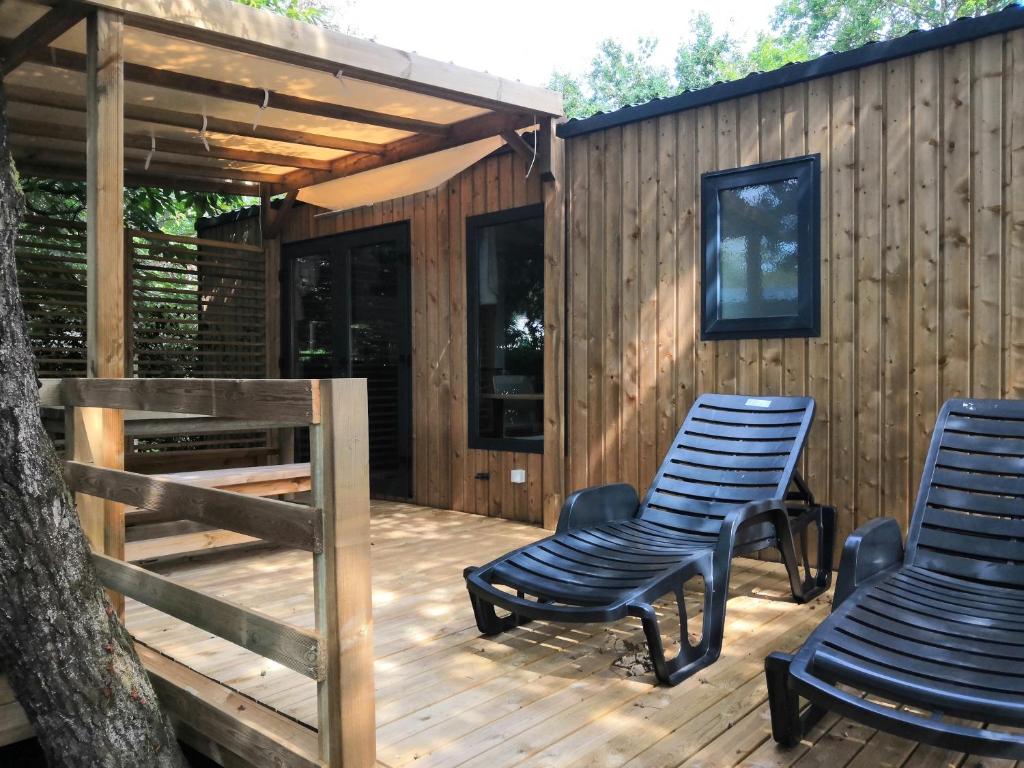 2 chaises sur une terrasse à côté d'une cabine dans l'établissement Mobil Home camping 5 étoiles Biscarrosse, à Biscarrosse