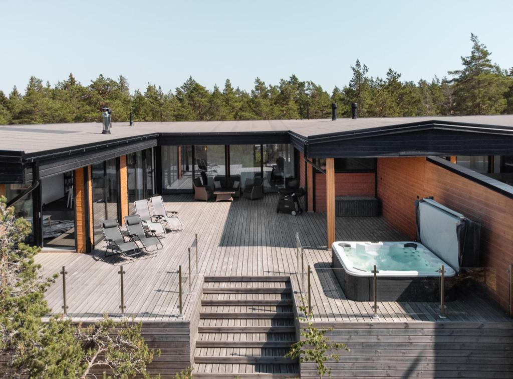 uma casa com um grande deque com uma banheira de hidromassagem em Seija's Modern Secluded Villa with Jacuzzi & Sauna em Töfsala