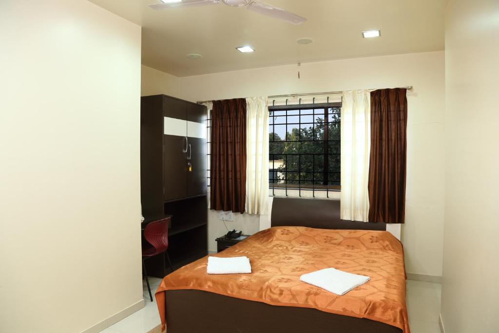 a bedroom with a bed with two towels on it at Hotel Shreyas in Pune