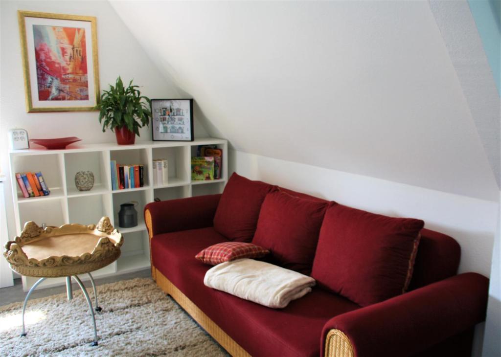 sala de estar con sofá rojo y estante para libros en Ferienwohnung Heimelich en Rastede