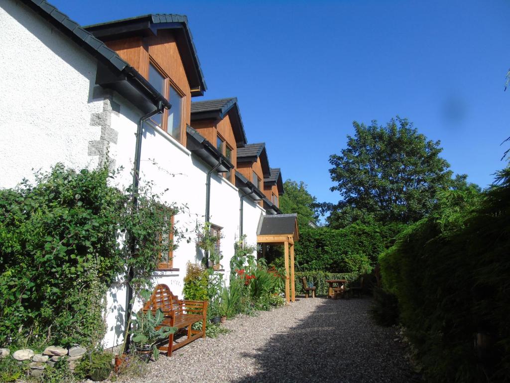 a white building with a pathway next to a house at Craik Na Dav B&B in Invermoriston