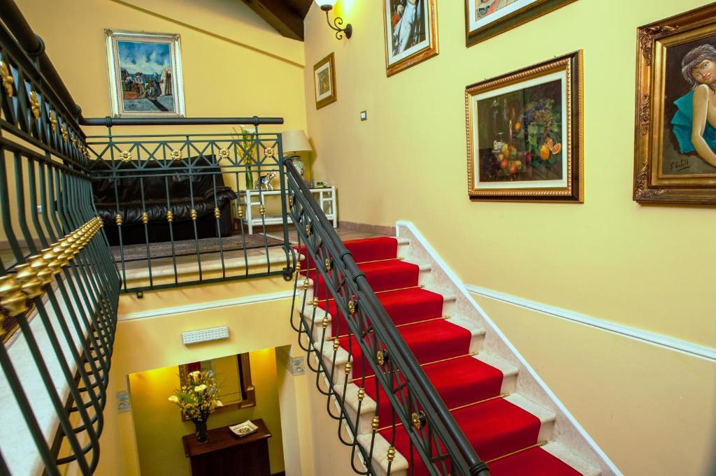 una escalera con alfombras rojas y pinturas en la pared en B&B Tribunale, en Cosenza