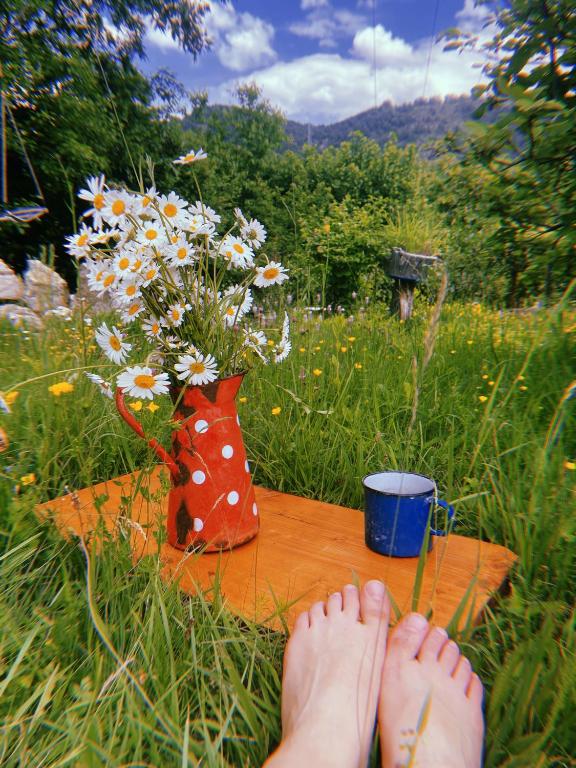 a persons feet on a table with a cup and flowers at Kokin Brod Apartments in Kokin Brod