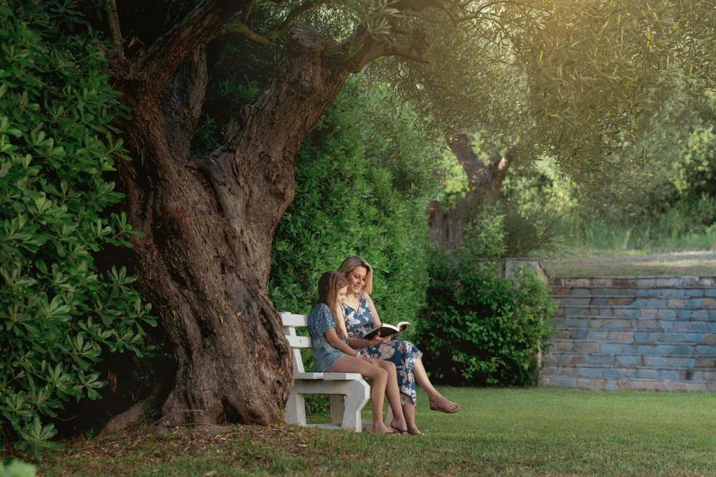 a woman sitting on a bench under a tree at Julia Hotel in Fourka