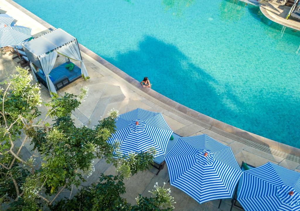 un grupo de sombrillas azules y blancas junto a una piscina en Pakasai Resort - SHA Extra plus en Ao Nang Beach