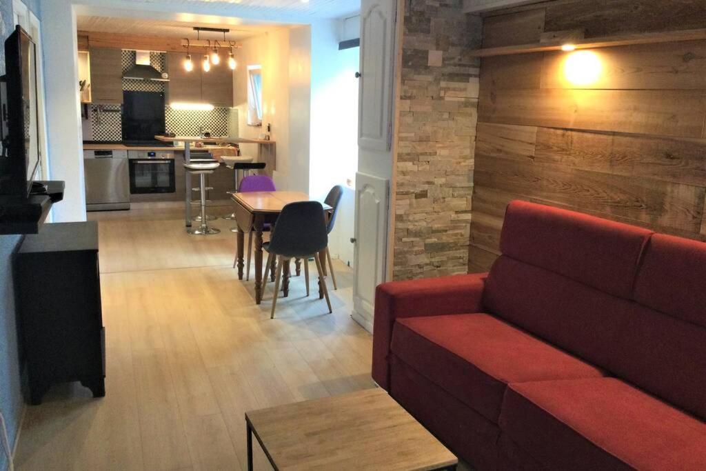 sala de estar con sofá rojo y cocina en Grand T2 4 voyageurs tout confort en Cauterets