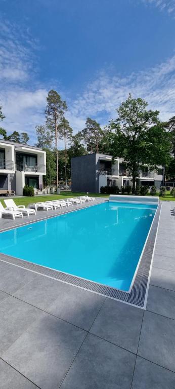 a large blue swimming pool with chairs and a building at Leo Royal Apartament Pobierowo in Pobierowo