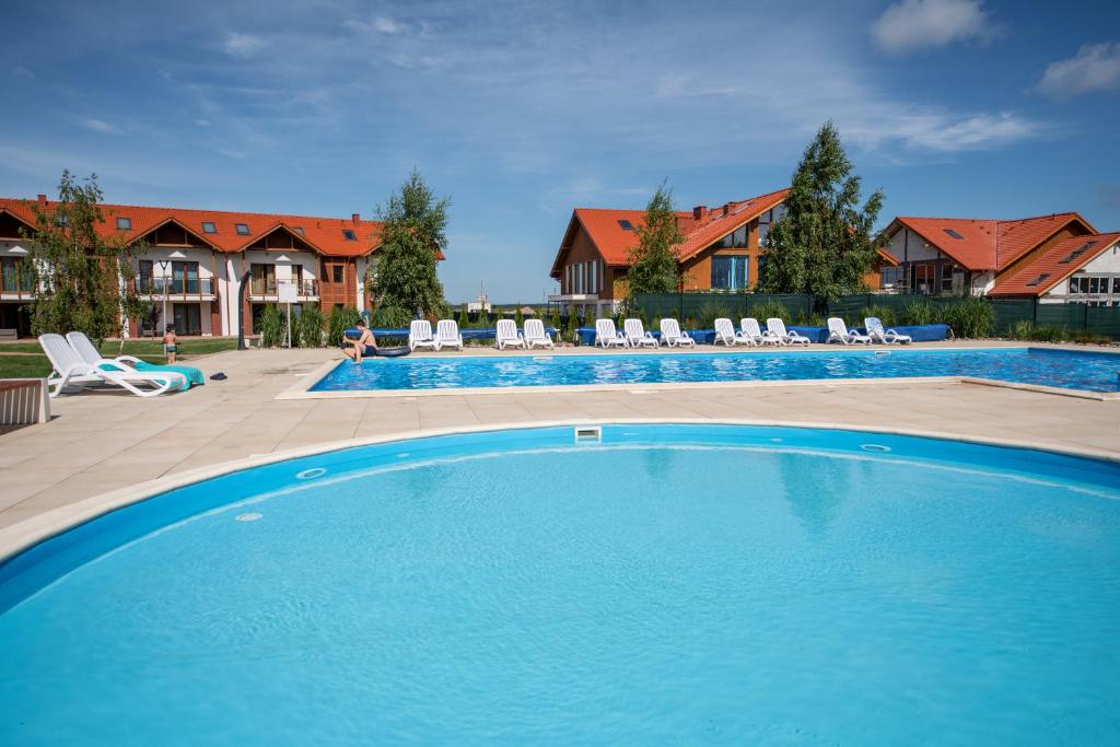 une grande piscine avec des chaises et une maison dans l'établissement Łebska Ostoja - AKS, à Żarnowska