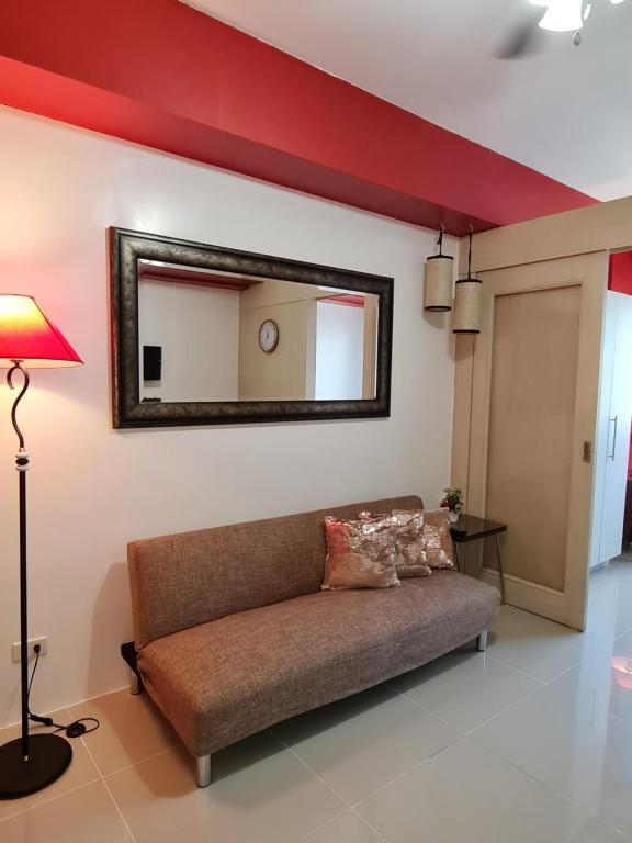 a living room with a couch and a mirror at Sea Residences - Condo R Us in Manila