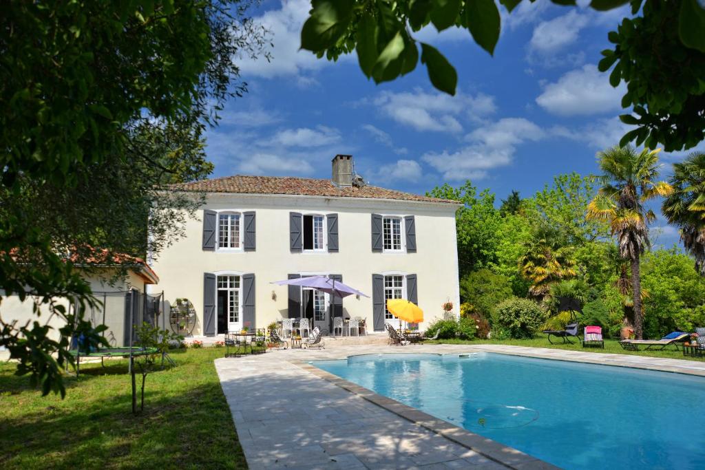 uma grande casa branca com uma piscina em frente em Maison Matachot em Orthez