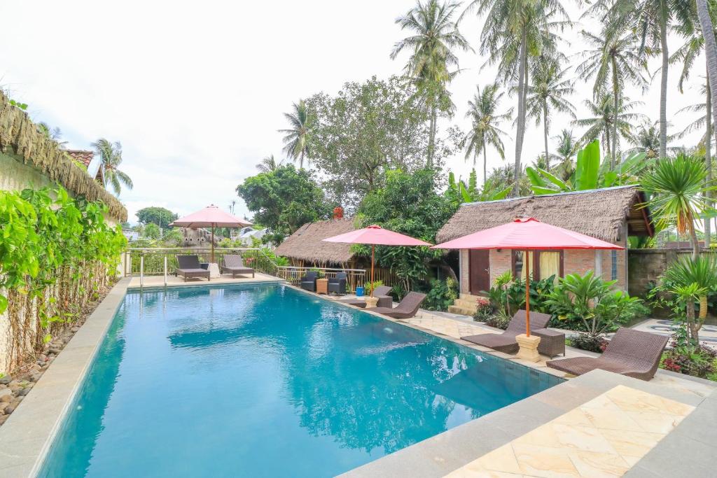 a pool at a resort with chairs and umbrellas at Senggigi Cottages Lombok in Senggigi