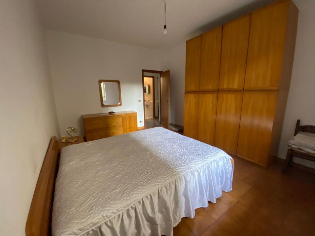 sypialnia z białym łóżkiem i drewnianymi szafkami w obiekcie Appartamento mare e relax w mieście Gioiosa Marea