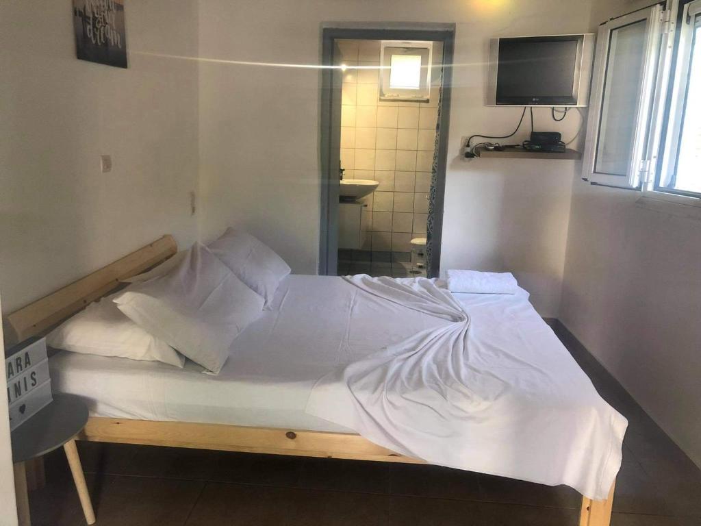un letto con lenzuola e cuscini bianchi in una stanza di Karampinis a Kali Limenes