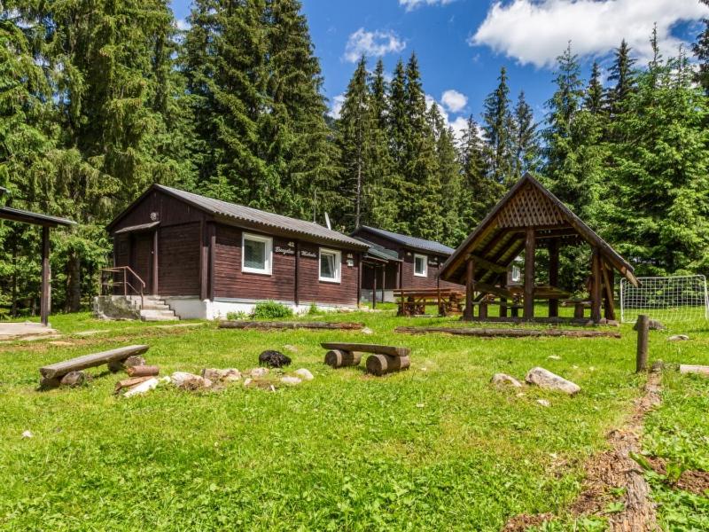 a log cabin in the woods with a grass yard at Chaty Jasná in Demanovska Dolina