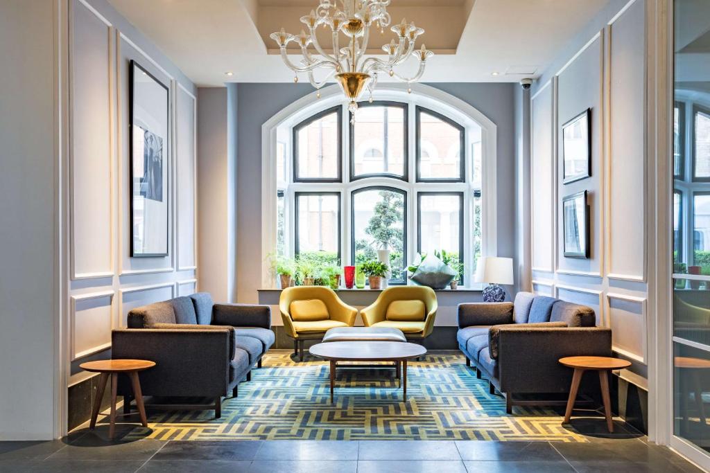a living room with couches and tables and a chandelier at Radisson Blu Hotel, London Bloomsbury in London