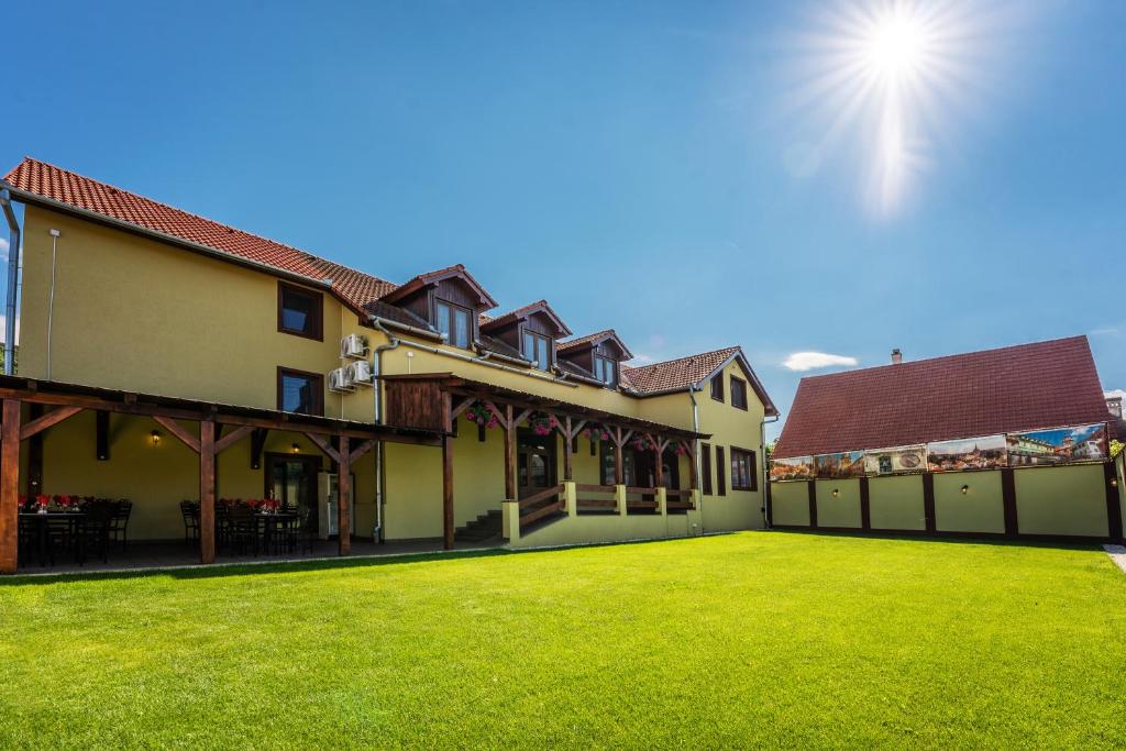 une maison avec une pelouse verte devant elle dans l'établissement Hotel PrincesSophie, à Sighişoara