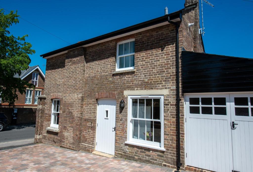 un edificio de ladrillo con puertas blancas y garaje en Southgate Coach House en Dorchester