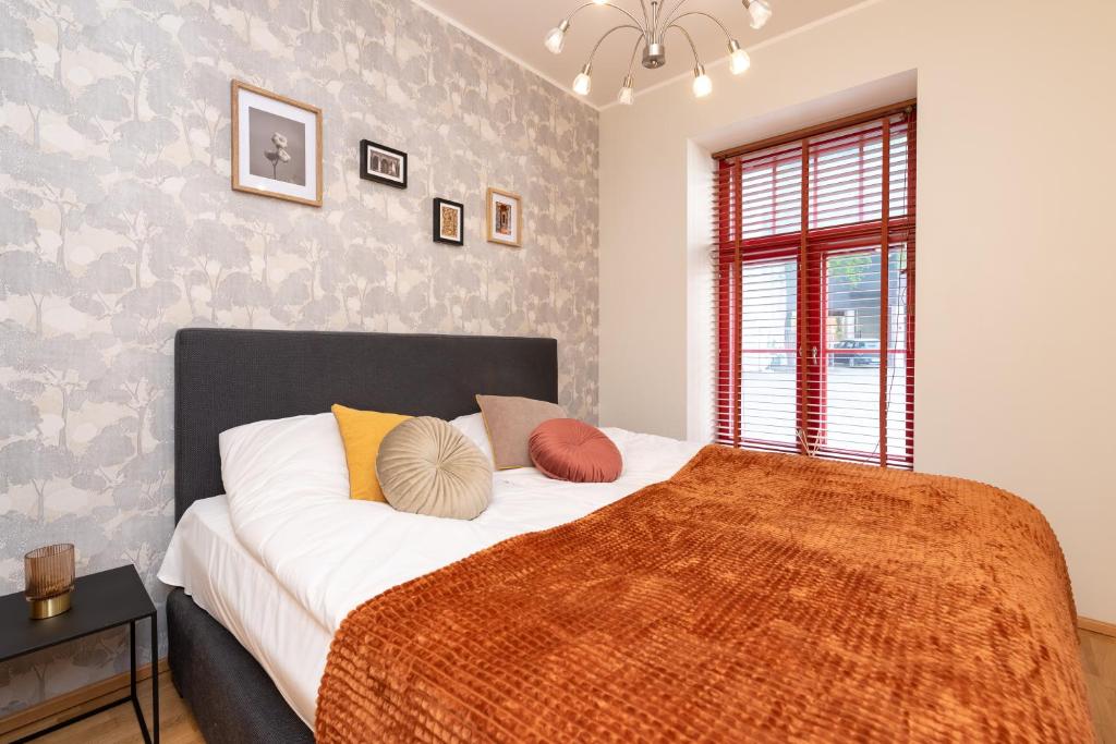 um quarto com uma cama grande e um cobertor laranja em Stylish apartment with parking in Telliskivi em Talin