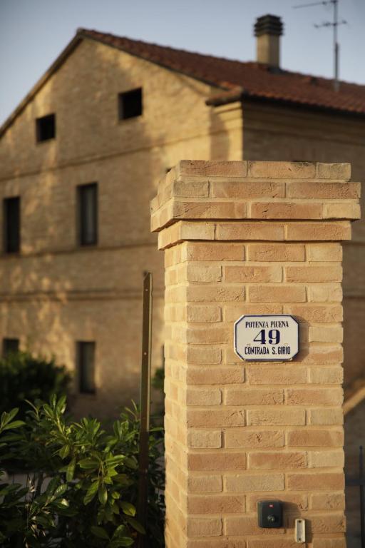 a brick wall with a sign in front of a building at Agriturismo La Fonte di San Girio in Potenza Picena