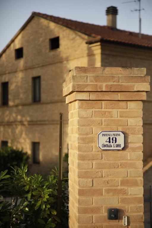 una pared de ladrillo con un cartel delante de un edificio en Agriturismo La Fonte di San Girio, en Potenza Picena