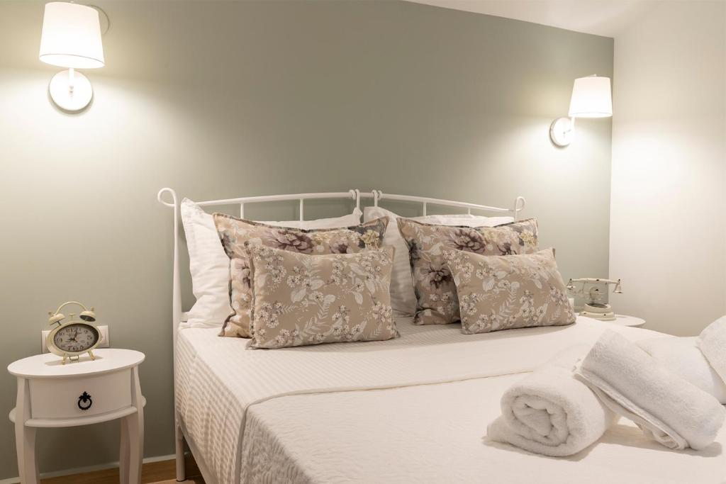 een slaapkamer met een wit bed met kussens en een klok bij Villa La Varik 2 in Litóchoron