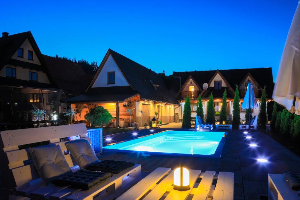a swimming pool in the backyard of a house at night at Willa Dream z basenem i jacuzzi in Poronin