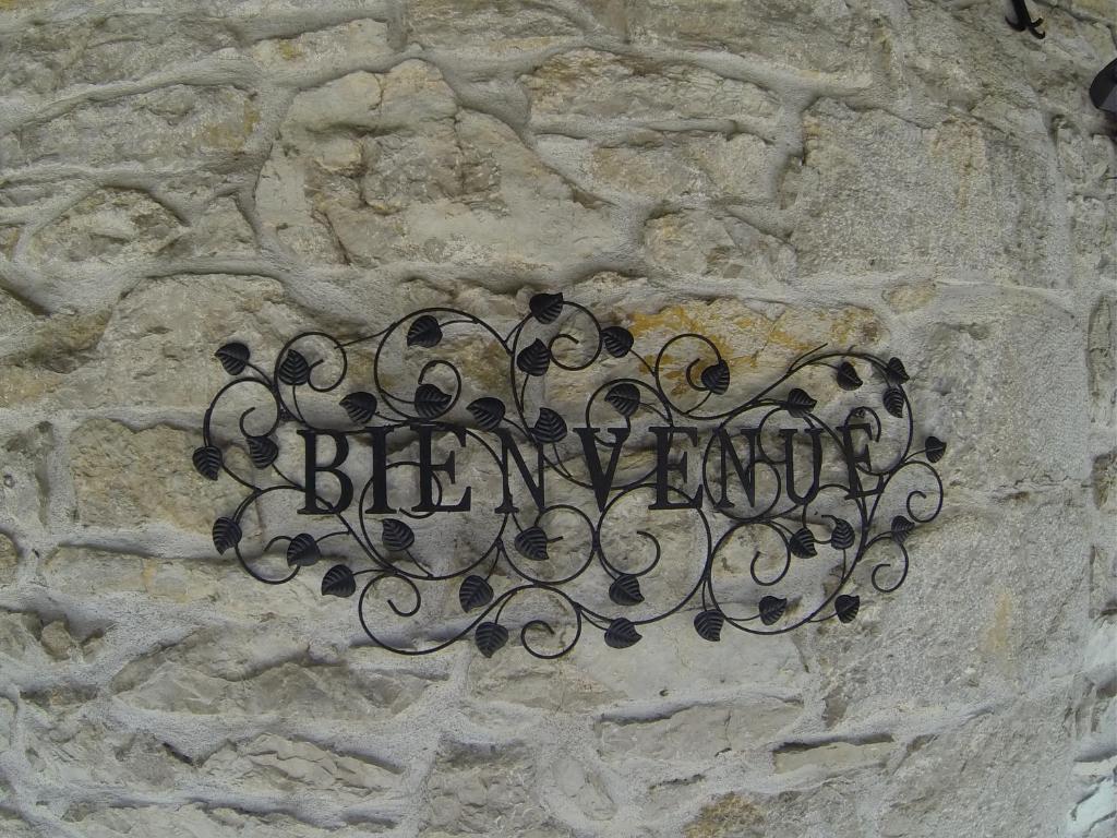 a metal sign on the side of a stone wall at Auberge de la Sagne in Cabrerets