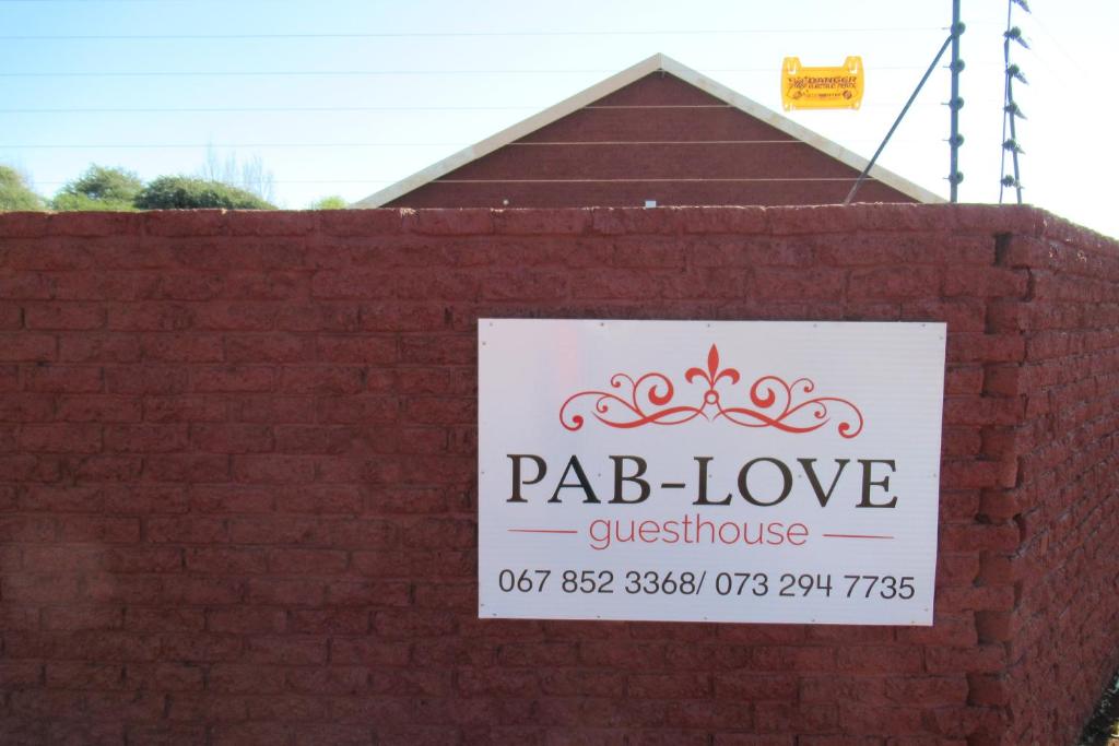 a sign for aqb love questionnaire on a brick wall at Pab-Love Guest House in Kuruman