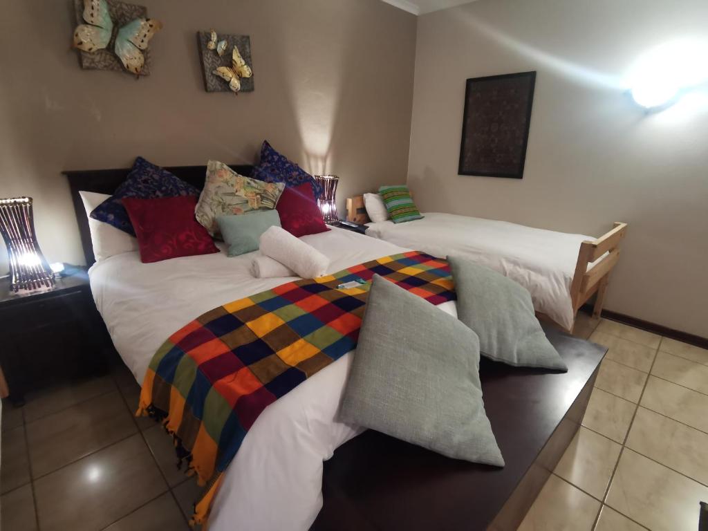 een slaapkamer met 2 bedden en kleurrijke kussens bij Harties 2 Sleeper Double Room with Private Bathroom in Hartbeespoort