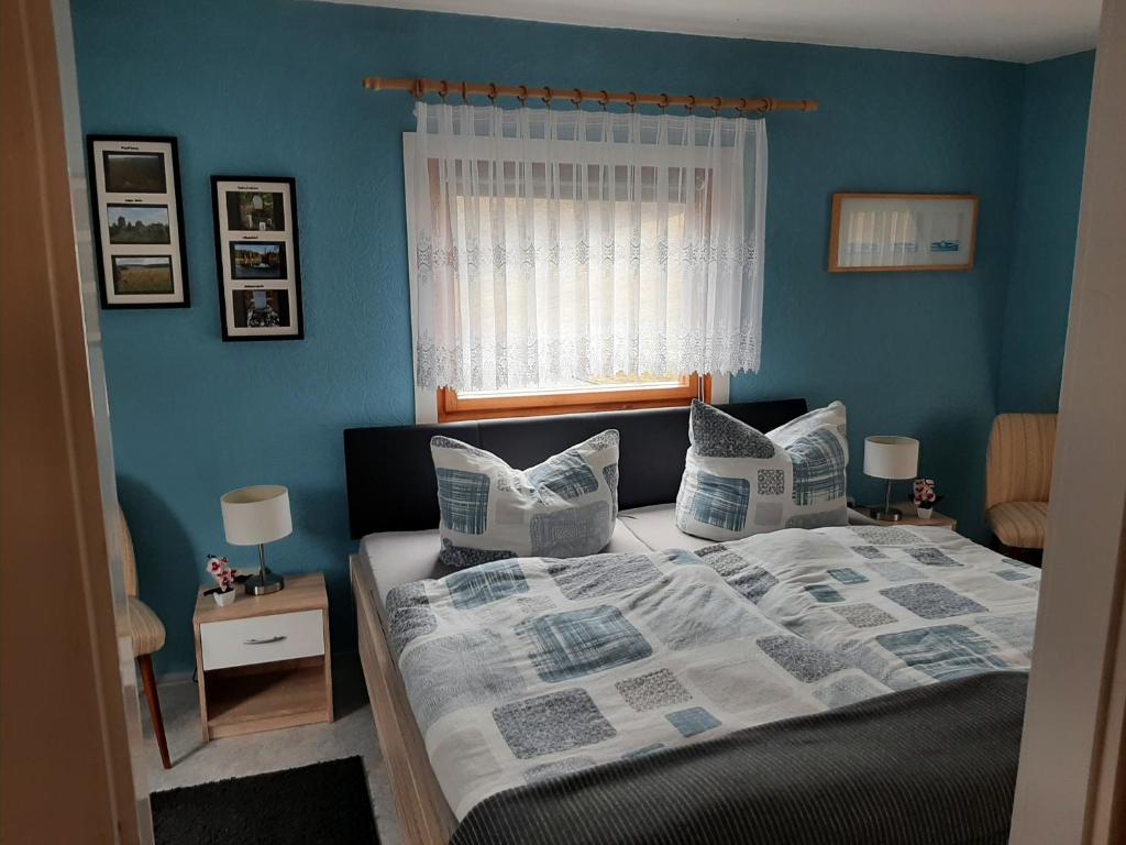 um quarto com uma cama com paredes azuis e uma janela em Ferienhaus Rosemarie Erlbach Vogtland em Erlbach