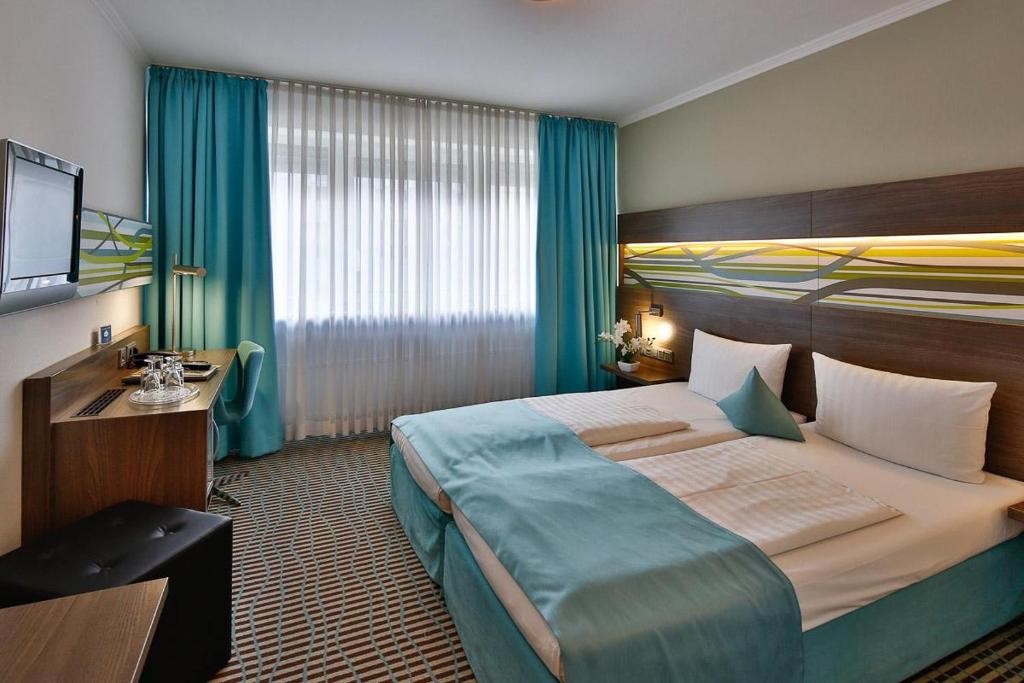 ミュンヘンにあるホテル ヴァリスの大型ベッドとテレビが備わるホテルルームです。