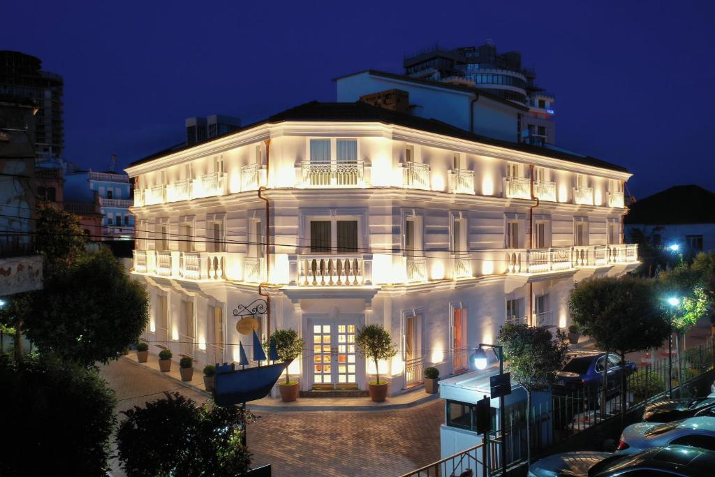 a large white building at night with lights at Giulia Albérgo Hotel in Durrës