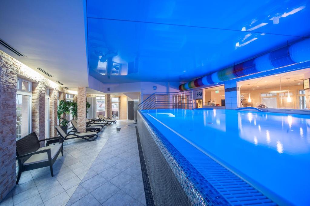 a large swimming pool in a building with blue lighting at SkyHotelGwarna in Legnica