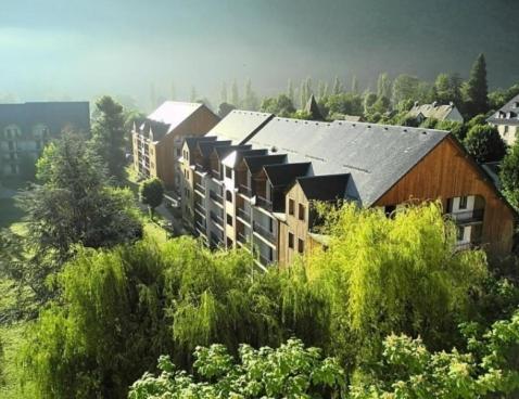 a group of buildings on a hill with trees at Les jardins Ramel in Luchon