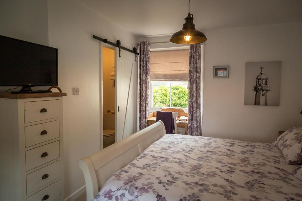 a bedroom with a bed and a tv and a window at Stone's throw Cottage Mevagissey in Mevagissey