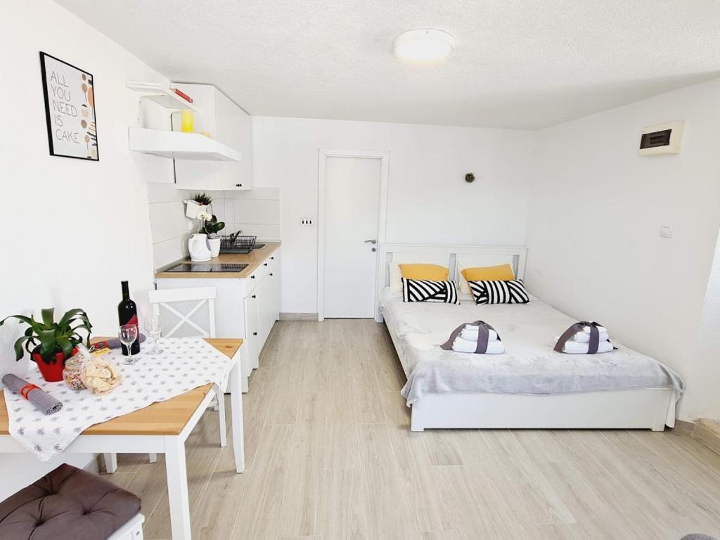 ein weißes Schlafzimmer mit 2 Betten und einem Tisch in der Unterkunft Waterfront studio overlooking The Old city in Korčula