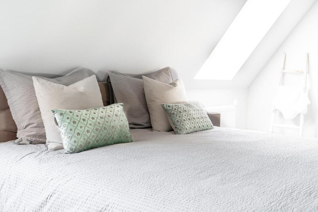 een wit bed met verschillende kussens erop bij 99 Lifestyle Suite in Zwaag
