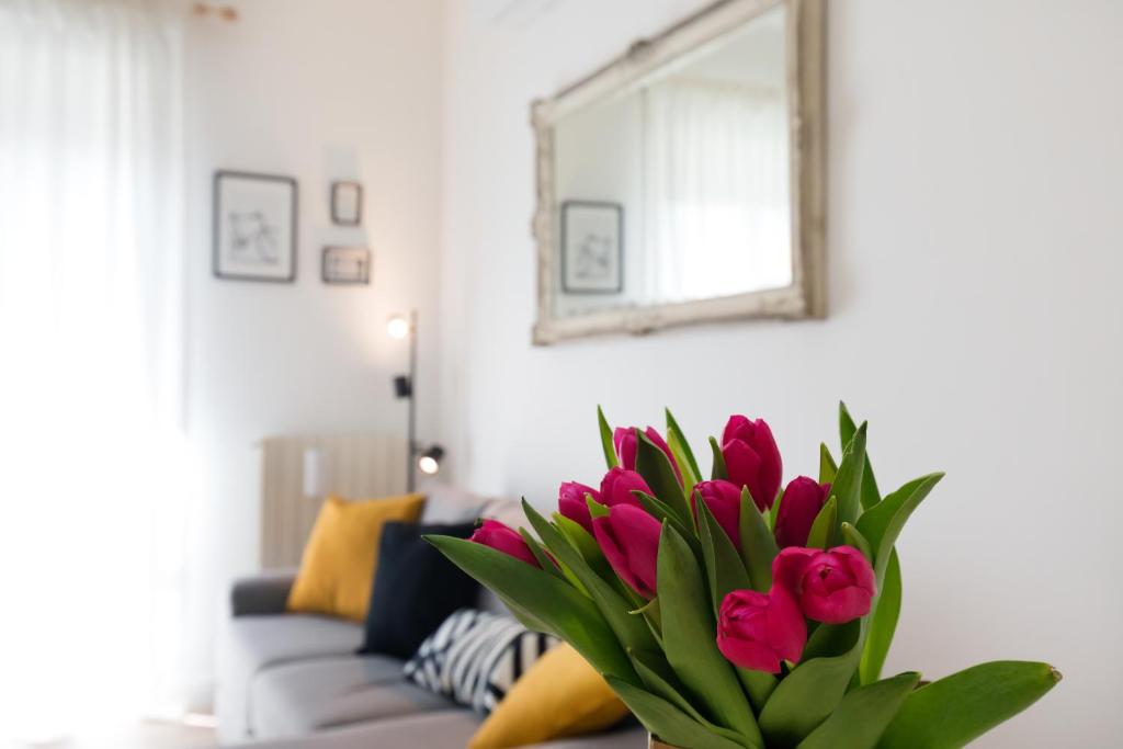 a vase of pink tulips in front of a couch at Maison Madeleine Rome in Rome