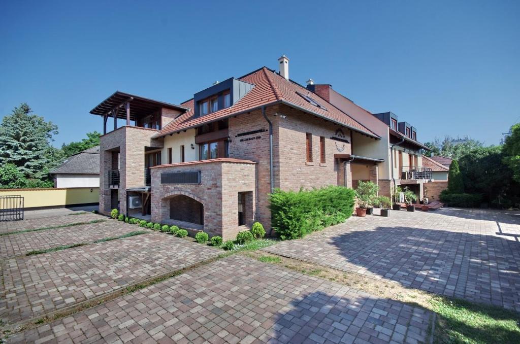 a large brick house with a brick driveway at Várfürdő Panzió Gyula in Gyula