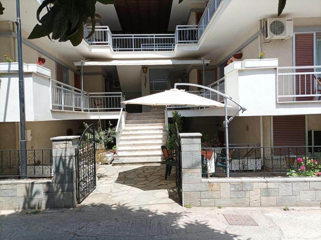 - un bâtiment avec une terrasse avec un parasol et des escaliers dans l'établissement Vanta Studio, à Thasos