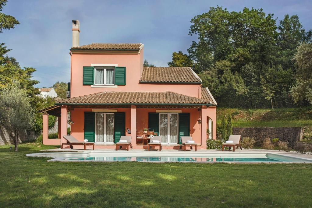 a pink house with a pool in front of it at Quercus Villa, Achilleion Palace, Corfu in Perama