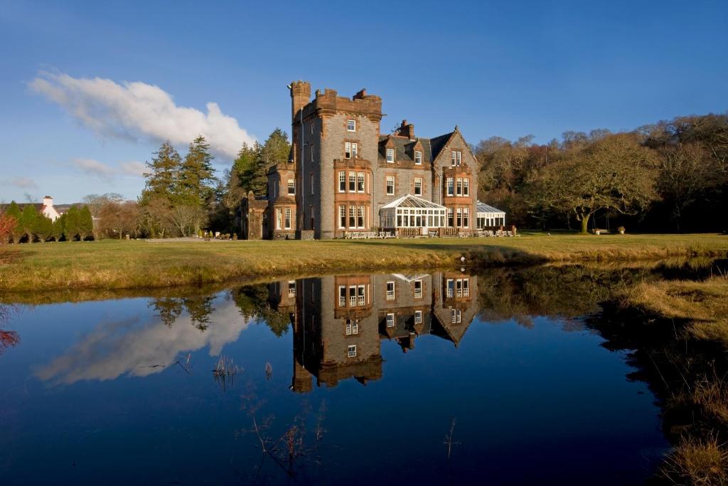 un antiguo castillo con su reflejo en el agua en Isle of Eriska Hotel Spa & Island, en Benderloch