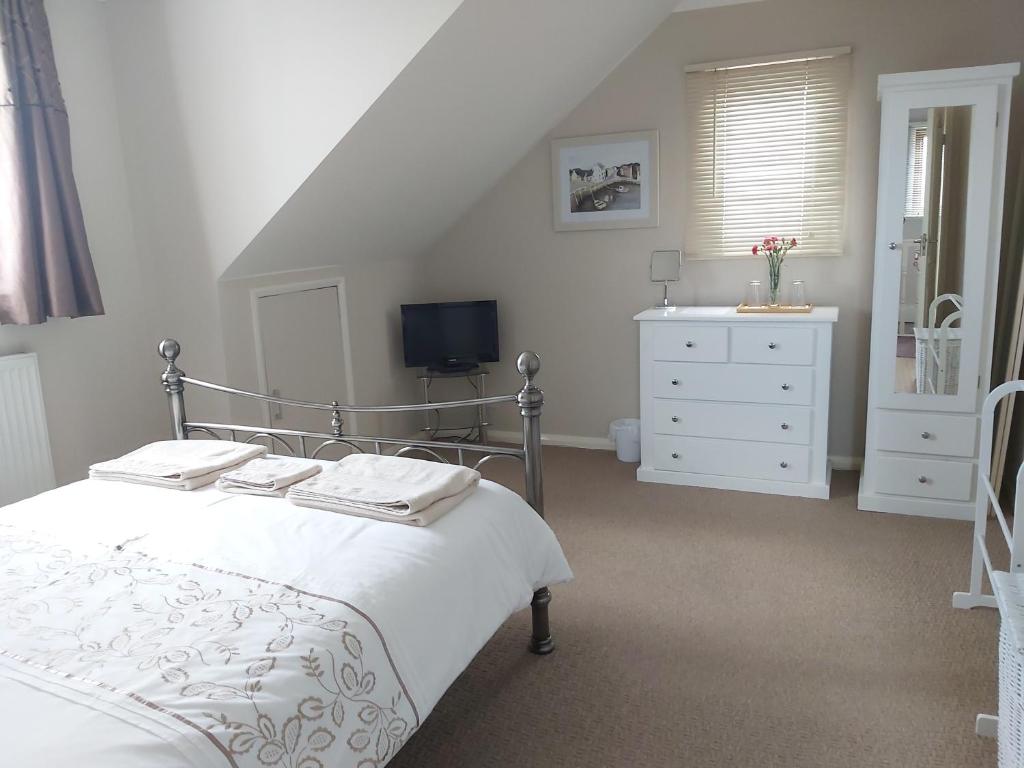 a bedroom with a bed and a dresser and a tv at The Gem in Winchelsea