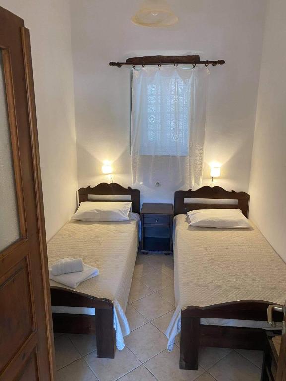 two beds in a small room with a window at Pension Sofia Amorgos-Katapola in Katapola