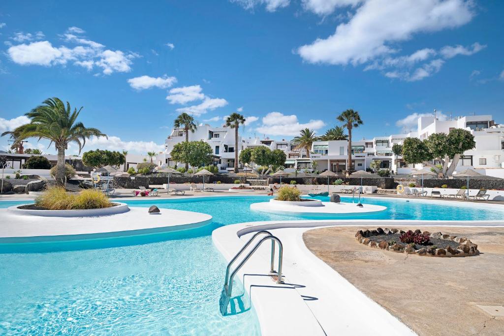 - une piscine dans un complexe avec des palmiers et des bâtiments dans l'établissement Calimar Los Molinos, à Costa Teguise